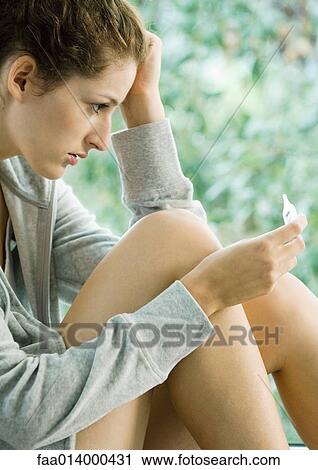 Woman holding head, looking at thermometer View Large Photo Image Stock Image - Woman holding head, looking at thermometer. Fotosearch