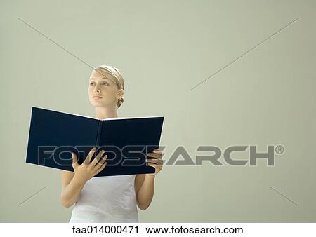 Woman holding open book, looking away View Large Photo Image Stock Image - Woman holding open book, looking away. Fotosearch
