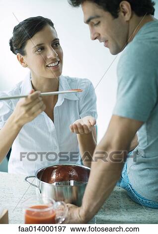 Woman holding up spoon of tomato sauce for man to taste View Large Photo Image Stock Photo - Woman holding up spoon of tomato sauce for man to taste. Fotosearch