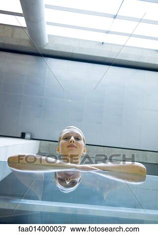 Stock Photo - Woman leaning against glass guard rail, low angle view. Fotosearch