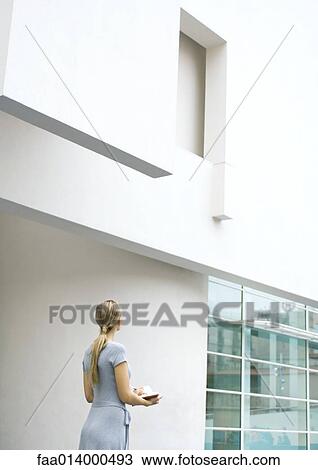 Woman standing, looking up at facade of building, taking notes View Large Photo Image Stock Image - Woman standing, looking up at facade of building, taking notes. Fotosearch
