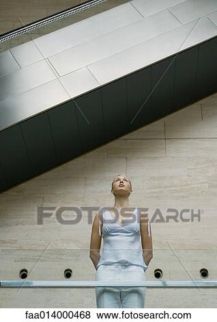 Woman standing under escalator, low angle view View Large Photo Image Stock Photo - Woman standing under escalator, low angle view. Fotosearch