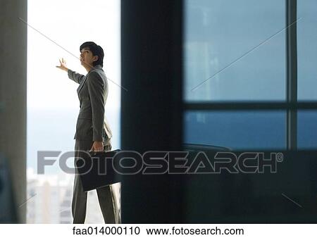 Woman standing with briefcase, next to bay window with arm out, looking over shoulder View Large Photo Image Stock Image - Woman standing with briefcase, next to bay window with arm out, looking over shoulder. Fotosearch
