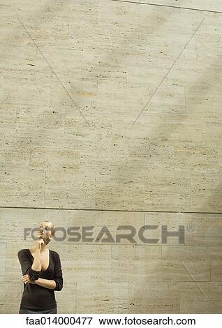 Woman standing with hand under chin View Large Photo Image Stock Photo - Woman standing with hand under chin. Fotosearch