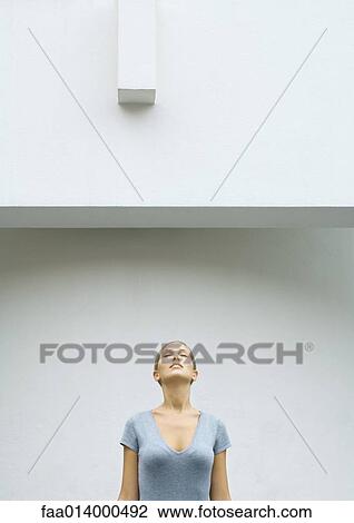 Stock Image - Woman standing with head back and eyes closed, waist up. Fotosearch