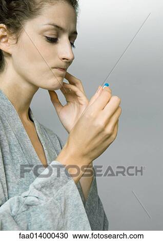Woman wearing bathrobe, holding up pill, making face View Large Photo Image Stock Image - Woman wearing bathrobe, holding up pill, making face. Fotosearch