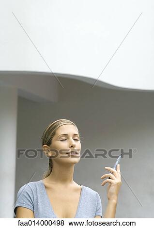 Stock Photo - Woman with eyes closed, holding up pen. Fotosearch