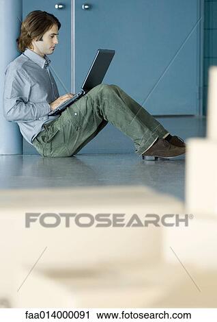 Young man sitting on floor using laptop, cardboard boxes in foreground View Large Photo Image Stock Image - Young man sitting on floor using laptop, cardboard boxes in foreground. Fotosearch