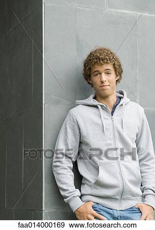 Young man standing with thumbs in pockets, looking at camera View Large Photo Image Stock Photo - Young man standing with thumbs in pockets, looking at camera. Fotosearch