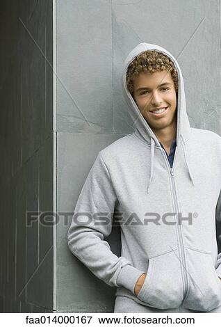 Stock Photo - Young man wearing hooded sweatshirt, smiling at camera. Fotosearch