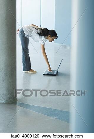 Young woman bending over, pressing key on laptop View Large Photo Image Stock Image - Young woman bending over, pressing key on laptop. Fotosearch