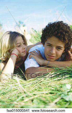 Boy and girl lying in grass View Large Photo Image Stock Image - Boy and girl lying in grass. Fotosearch