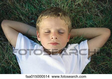 Boy lying on grass with hands behind head View Large Photo Image Picture - Boy lying on grass with hands behind head. Fotosearch