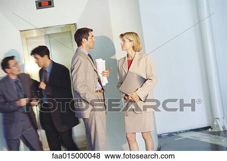 Business associates talking by elevator View Large Photo Image Stock Photo - Business associates talking by elevator. Fotosearch
