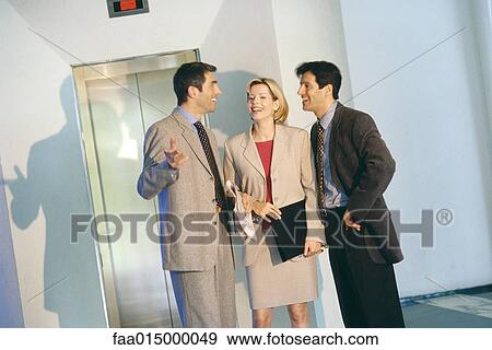 Business associates talking by elevator View Large Photo Image Stock Photo - Business associates talking by elevator. Fotosearch