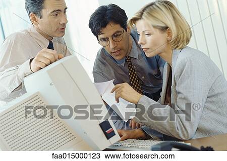 Stock Image - Business associates working at desktop computer. Fotosearch