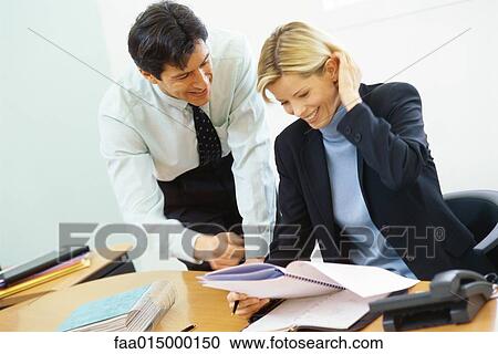 Business colleagues, man leaning over woman's shoulder, pointing to documents View Large Photo Image Stock Image - Business colleagues, man leaning over woman's shoulder, pointing to documents. Fotosearch