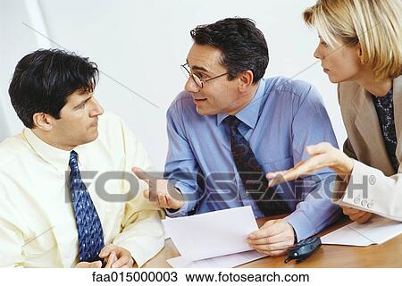 Stock Image - Business colleagues questioning associate. Fotosearch