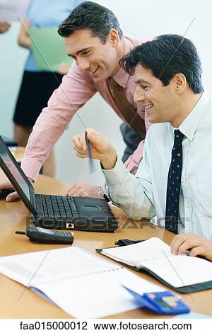 Business colleagues using laptop together, smiling View Large Photo Image Stock Image - Business colleagues using laptop together, smiling. Fotosearch