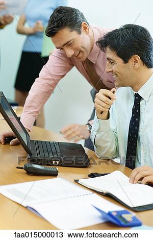 Business colleagues using laptop together, smiling View Large Photo Image Stock Image - Business colleagues using laptop together, smiling. Fotosearch