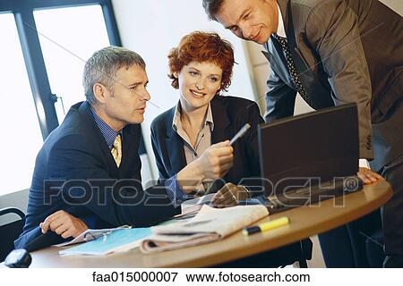 Stock Photo - Business colleagues using laptop. Fotosearch