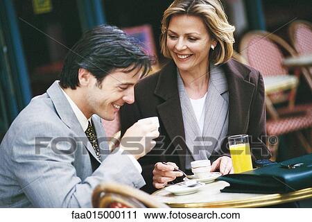 Stock Image - Businessman and woman sitting at sidewalk cafe. Fotosearch