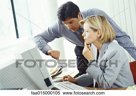 Businessman leaning over female colleague's shoulder looking at monitor View Large Photo Image Stock Photography - Businessman leaning over female colleague's shoulder looking at monitor. Fotosearch