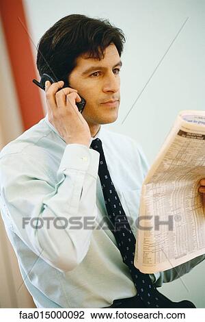 Businessman using phone and holding up financial section of newspaper View Large Photo Image Stock Image - Businessman using phone and holding up financial section of newspaper. Fotosearch