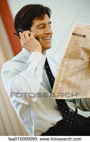 Businessman using phone and holding up financial section of newspaper, smiling View Large Photo Image Stock Image - Businessman using phone and holding up financial section of newspaper, smiling. Fotosearch