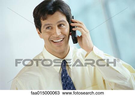 Stock Image - Businessman using phone, smiling. Fotosearch