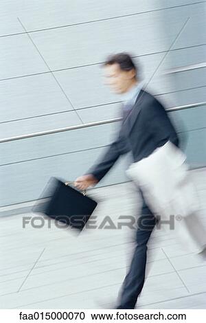 Businessman walking with briefcase and jacket over arm, blurred motion View Large Photo Image Stock Image - Businessman walking with briefcase and jacket over arm, blurred motion. Fotosearch