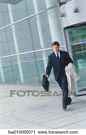 Businessman walking with briefcase and jacket over arm, blurred motion View Large Photo Image Stock Image - Businessman walking with briefcase and jacket over arm, blurred motion. Fotosearch