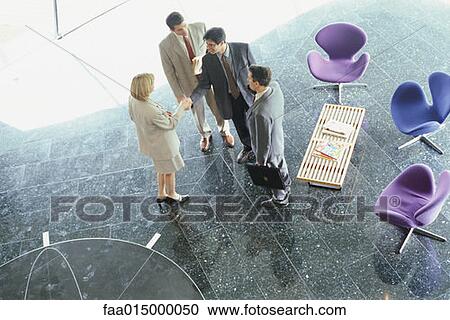 Businesswoman greeting businessmen in lobby, high angle view View Large Photo Image Stock Image - Businesswoman greeting businessmen in lobby, high angle view. Fotosearch