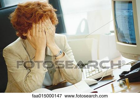 Businesswoman sitting at desk, holding head View Large Photo Image Stock Photo - Businesswoman sitting at desk, holding head. Fotosearch