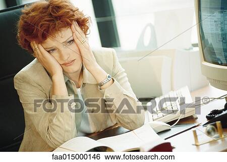 Businesswoman sitting at desk, holding head View Large Photo Image Stock Photograph - Businesswoman sitting at desk, holding head. Fotosearch