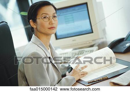 Businesswoman sitting at desk View Large Photo Image Stock Image - Businesswoman sitting at desk. Fotosearch