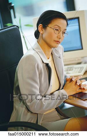 Businesswoman sitting at desk View Large Photo Image Stock Image - Businesswoman sitting at desk. Fotosearch