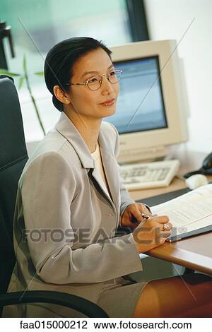 Businesswoman sitting at desk View Large Photo Image Stock Image - Businesswoman sitting at desk. Fotosearch