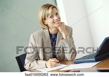 Businesswoman sitting at desk View Large Photo Image Stock Image - Businesswoman sitting at desk. Fotosearch
