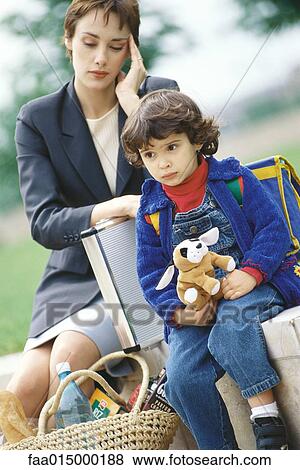 Businesswoman sitting with son, holding head View Large Photo Image Stock Photo - Businesswoman sitting with son, holding head. Fotosearch