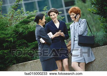 Businesswoman standing in office park, chatting View Large Photo Image Stock Image - Businesswoman standing in office park, chatting. Fotosearch