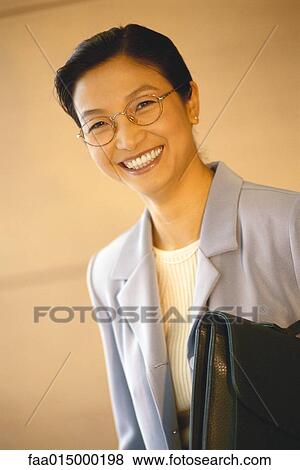 Stock Photo - Businesswoman standing with briefcase underarm, portrait. Fotosearch