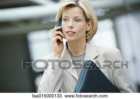 Businesswoman using phone, holding laptop View Large Photo Image Stock Image - Businesswoman using phone, holding laptop. Fotosearch