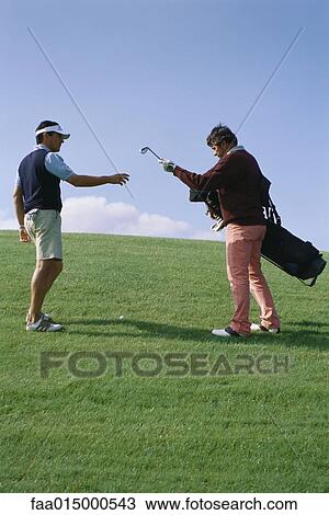 Stock Image - Caddy handing golfer golf club. Fotosearch