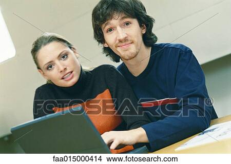 Picture - Couple using laptop, looking at camera. Fotosearch