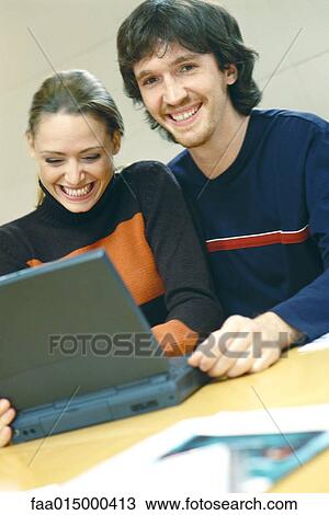 Couple using laptop, smiling View Large Photo Image Stock Image - Couple using laptop, smiling. Fotosearch