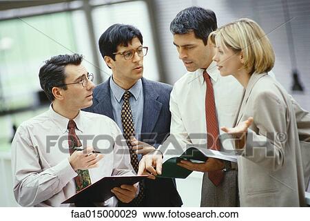 Four business colleagues standing discussing document and agenda View Large Photo Image Stock Photo - Four business colleagues standing discussing document and agenda. Fotosearch