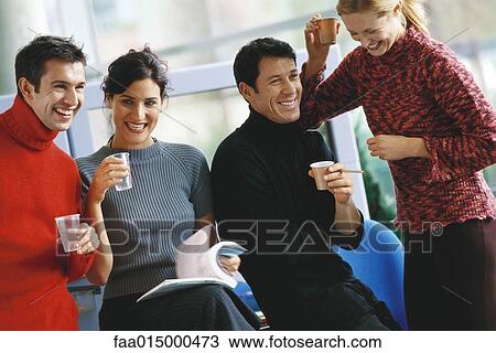 Stock Image - Four colleagues, holding cups of coffee and water, laughing. Fotosearch