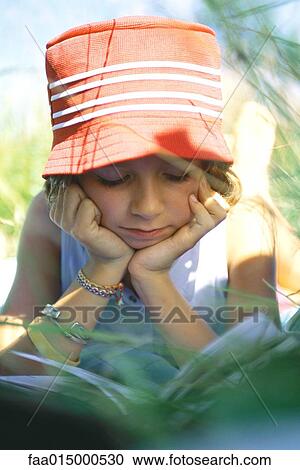 Girl lying in grass, reading View Large Photo Image Stock Image - Girl lying in grass, reading. Fotosearch