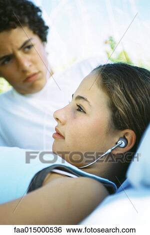Girl sharing earphones with friend View Large Photo Image Stock Photograph - Girl sharing earphones with friend. Fotosearch